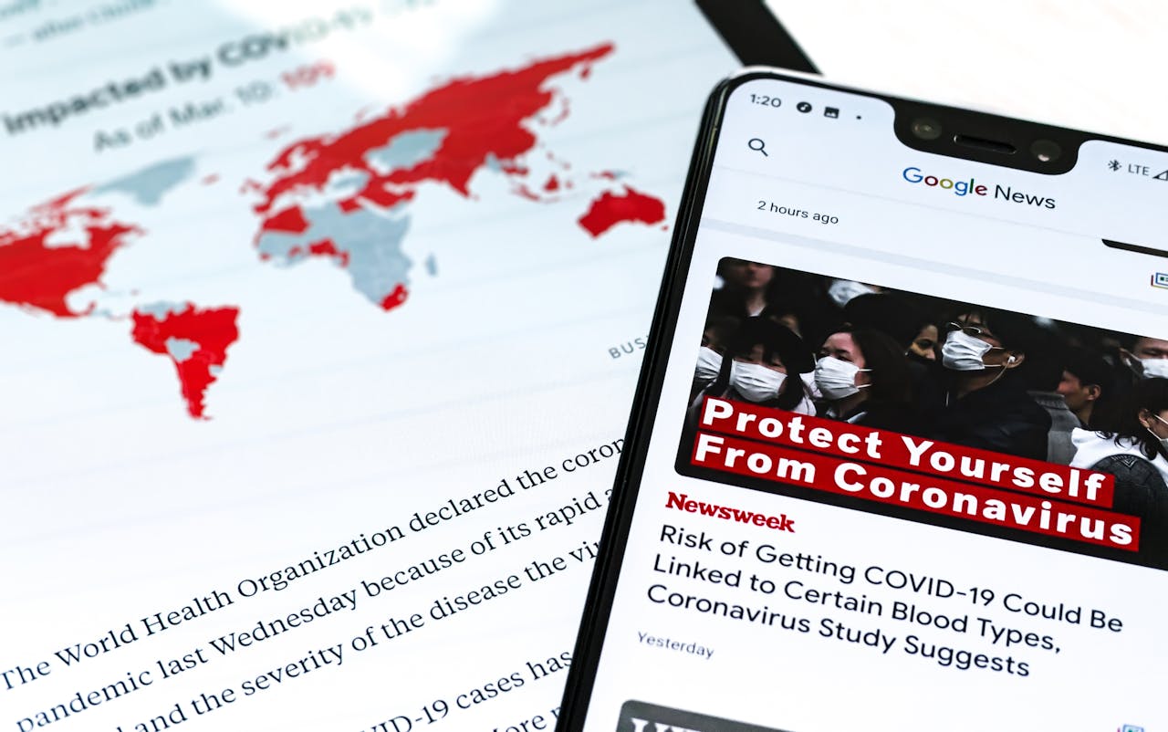 Smartphone with coronavirus updates and world map showing the impact of COVID-19.